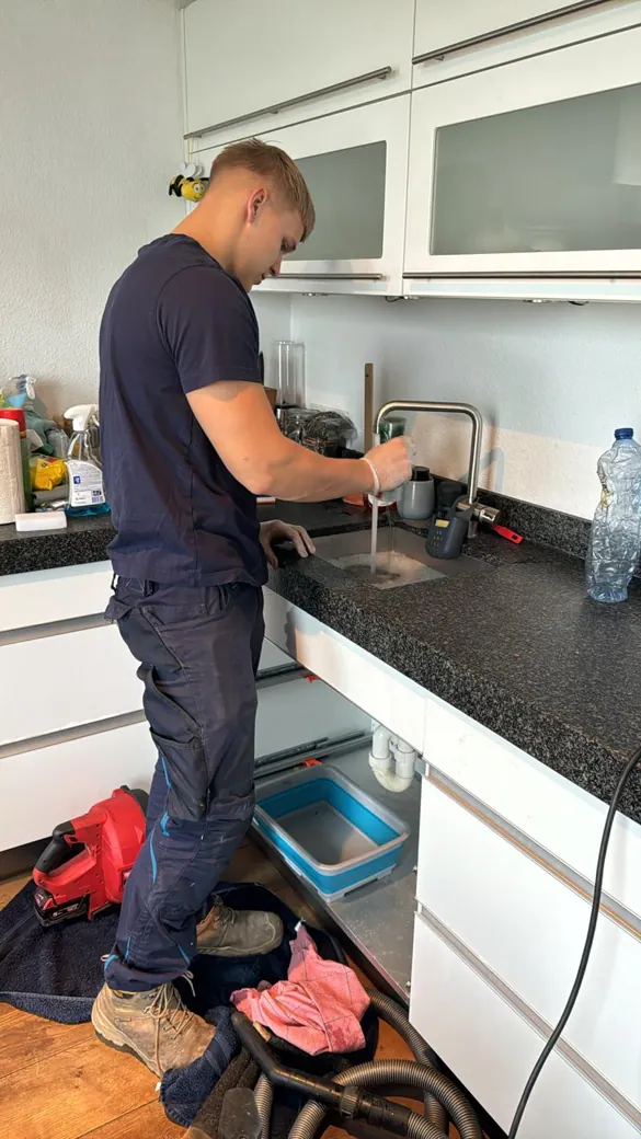 Monteur controleert en ontstopt een keukenafvoer onder de gootsteen