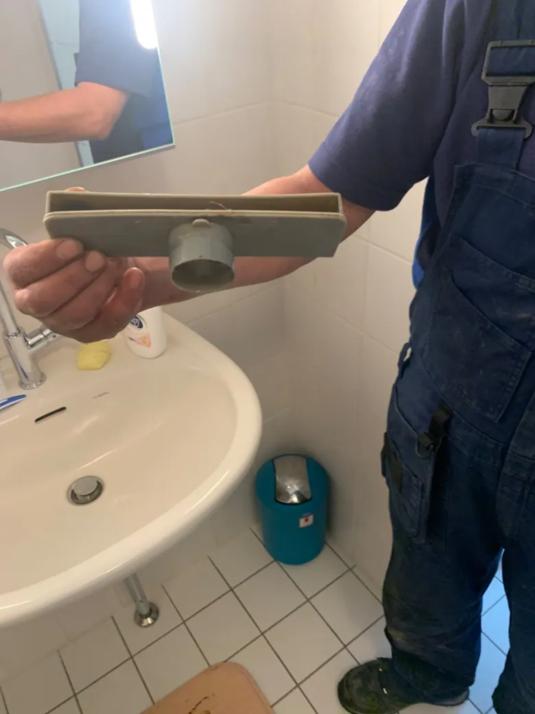 Monteur inspecteert een wastafelafvoer en sifon - praktijkbeeld