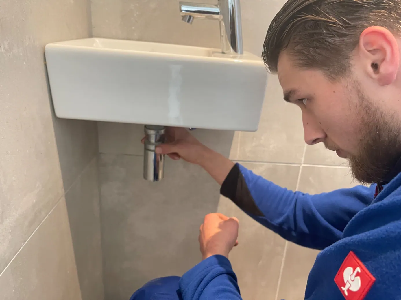 Monteur inspecteert een wastafelafvoer en sifon